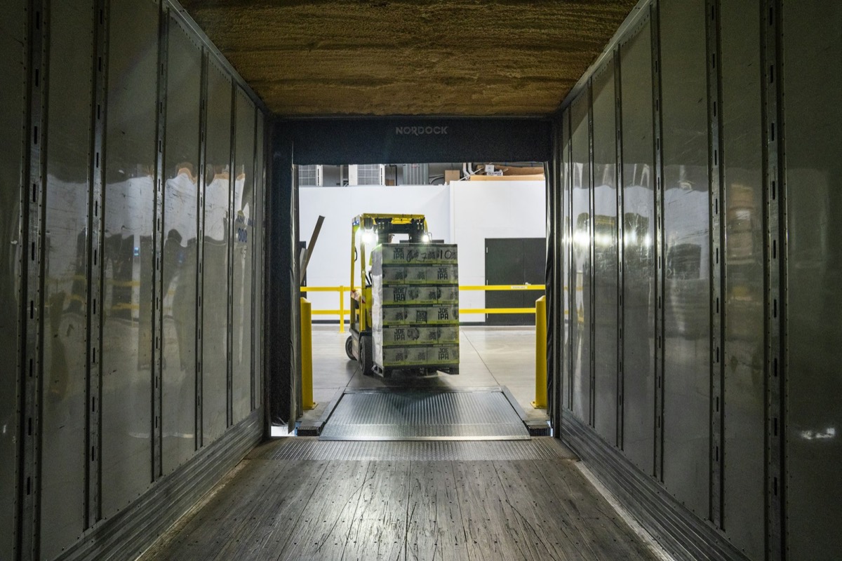 Forklift crossing a dock leveler while loading a trailer