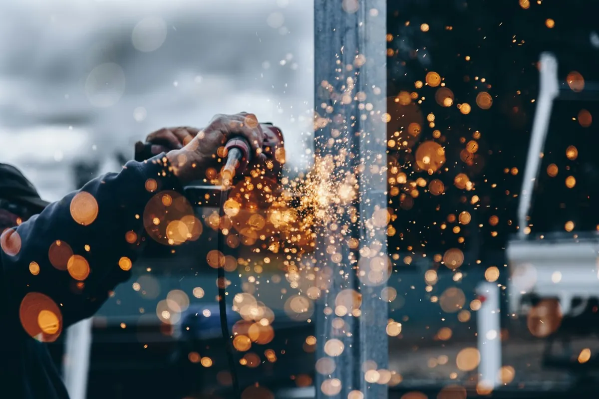 Sparks flying as a technician grinds steel during a door repair